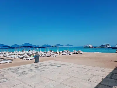 a beach with chairs and umbrellas and the ocean at Hurghada Resort in Hurghada
