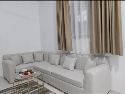 a white living room with a white couch and a table at Desert Daisy in Luxor
