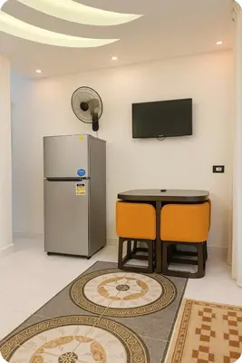 a room with a refrigerator and a table and chairs at Luxor Temple & Local Life at Your Doorstep Al FahadAprtments in Luxor