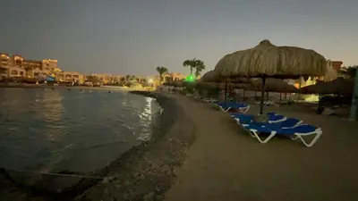 a beach with chairs and an umbrella and the water at Pause by The Sea Hurghada, Stay, Relax, Repeat in Hurghada