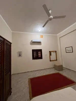 a living room with a ceiling fan and a red rug at Abdalla's House in Al Aqālitah