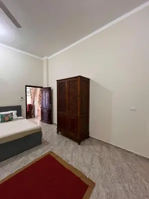 a bedroom with a bed and a wooden cabinet at Abdalla's House in Al Aqālitah