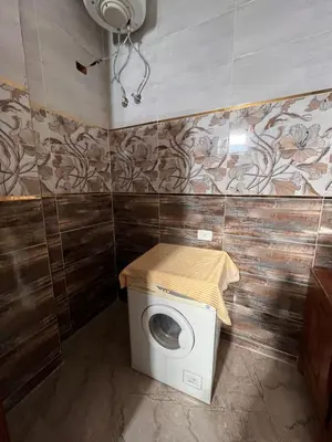 a bathroom with a washing machine with a towel on it at Abdalla's House in Al Aqālitah
