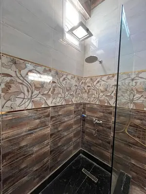 a bathroom with a shower with wooden walls at Abdalla's House in Al Aqālitah