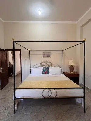 a bed with a black frame and white pillows at Abdalla's House in Al Aqālitah