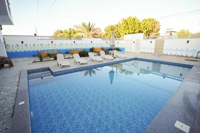a swimming pool with chairs and a table at Astralis Hotel in Al Aqālitah