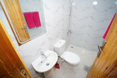 a white bathroom with a toilet and a sink at Astralis Hotel in Al Aqālitah