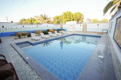 a swimming pool with chairs and a table at Astralis Hotel in Al Aqālitah
