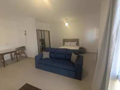 a living room with a blue couch and a bed at Magawish Studio #3 with pool view in Hurghada