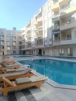 a swimming pool with lounge chairs in front of a building at Sea view Hotel Apartment in center in Hurghada