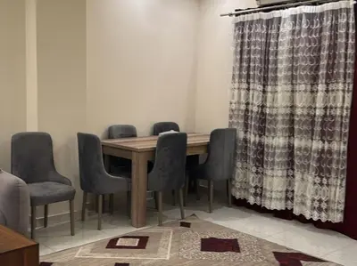 a dining room table with chairs and a curtain at Moon Apartment Hurghada in Hurghada