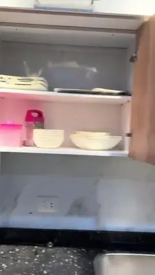 a refrigerator with bowls and utensils on a shelf at Moon Apartment Hurghada in Hurghada