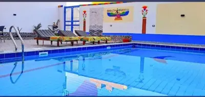 a large swimming pool with benches in a building at Alia House in Luxor
