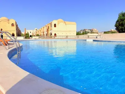 a large pool with blue water in front of a building at Saray ElOmda Wellness - Retreat Village in Al Karnak
