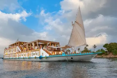 a sail boat in the water next to a building at Azhar II Dahabiya Luxury Nile Cruise in Luxor