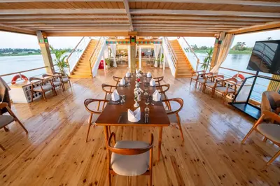 a dining room on a boat with tables and chairs at Azhar II Dahabiya Luxury Nile Cruise in Luxor