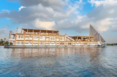 a large boat in the water with a building at Azhar II Dahabiya Luxury Nile Cruise in Luxor