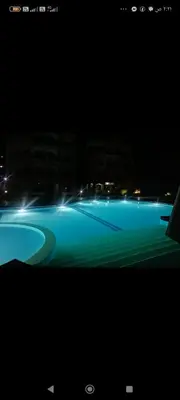 a swimming pool lit up at night with lights at Luxur sleep in Al Baghdādī