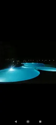 a row of pools lit up at night at Luxur sleep in Al Baghdādī