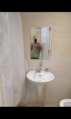 a man taking a picture of a sink in a bathroom at Luxur sleep in Al Baghdādī