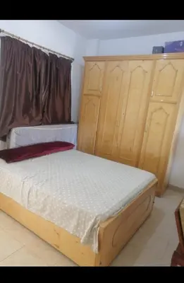 a bedroom with a bed and wooden cabinets at Luxur sleep in Al Baghdādī
