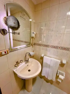 a bathroom with a sink and a mirror and towels at Jewel Luxor Hotel Nile View in Luxor