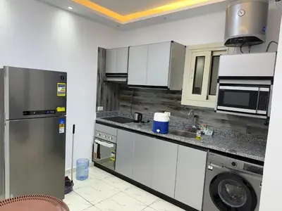 a kitchen with white cabinets and a stainless steel refrigerator at Turtles Beach Resort in Hurghada in Hurghada