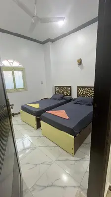 two beds in a white room with a window at Anas Nubian Guest House in Aswan