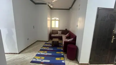 a living room with a red couch and a blue rug at Anas Nubian Guest House in Aswan
