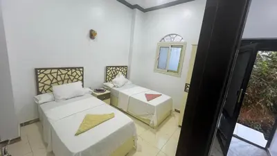 a room with two beds and a window at Anas Nubian Guest House in Aswan