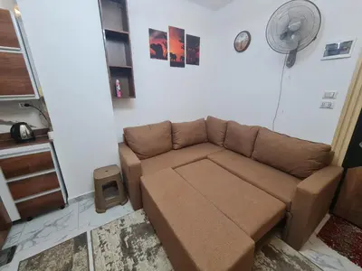 a brown couch in a living room with a fan at Modern Pool View 1BR with Balcony Prime Location on Hurghada Vibrant Promenade in Hurghada