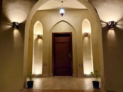 an empty hallway with a door and two potted plants at Bab Al Shams Palace in Luxor