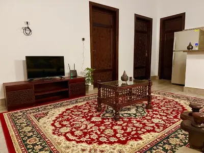 a living room with a red rug and a tv at Bab Al Shams Palace in Luxor