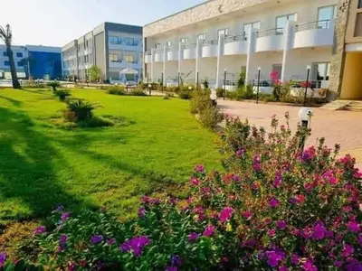 a green yard with flowers in front of a building at Cecelia Resort Hurghada in Hurghada