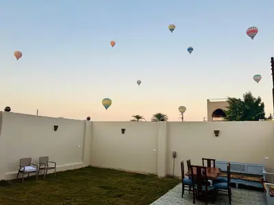 a patio with chairs and kites flying in the sky at West Mountain Home-Luxor in Al Aqālitah