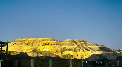 a large mountain is lit up at night at West Mountain Home-Luxor in Al Aqālitah