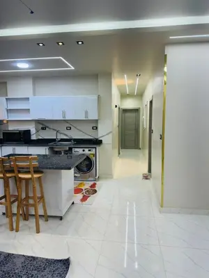 a kitchen with white cabinets and a table and chairs at شقة بالانتر الغردقة in Hurghada