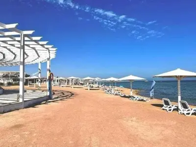 a beach with chairs and umbrellas and the ocean at Selena bay hurghada in Hurghada