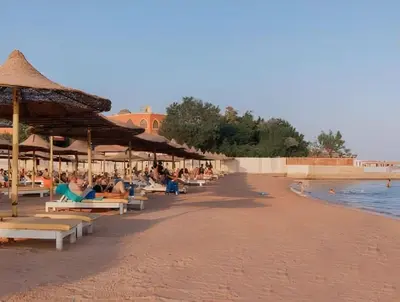 a beach with people sitting on chairs and umbrellas at AL Andalusia Hurghada in Hurghada