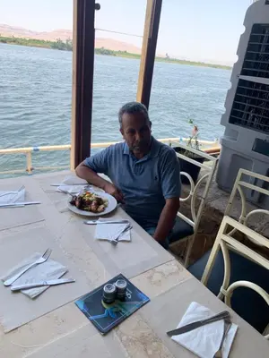 a man sitting at a table with a plate of food at Luxor is adorable! in Luxor