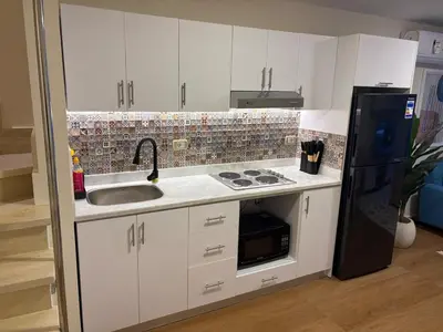 a kitchen with white cabinets and a black refrigerator at Duplex in Edelma Oldtown Sahl Hasheesh in Hurghada