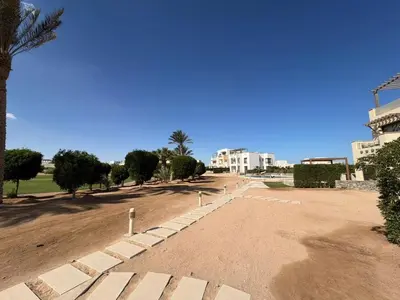 a park with a palm tree and buildings in the background at Cyan Elegant 3BR Golf View Escape in Hurghada