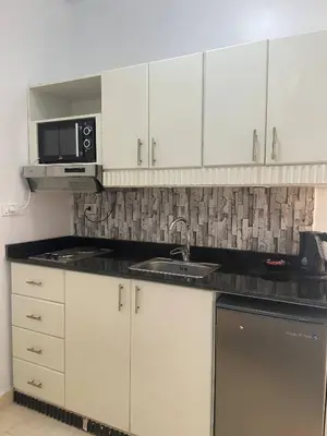 a kitchen with white cabinets and a sink and a microwave at Paradise at Tiba Al Ahyaa, Hurghada in Hurghada