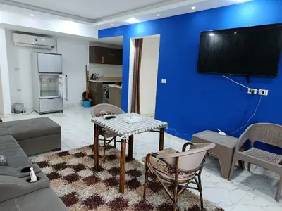 a living room with a couch and a tv on a blue wall at Fanadir Bay in Hurghada