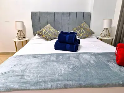 a bed with a blue blanket and two lamps at Gravity Sahl Hasheesh Not Egyptians in Hurghada
