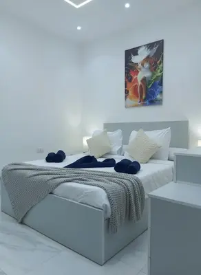 a white bedroom with a bed and a painting on the wall at Hurghada stylish Apartment on the beach in Hurghada