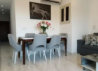 a dining room table with chairs and a vase of flowers at Hurghada stylish Apartment on the beach in Hurghada