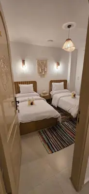 a hotel room with two beds and a chandelier at MaMa Africa Nubian Guest House in Aswan