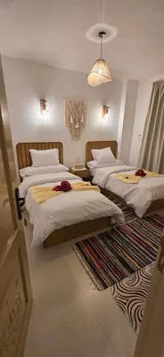 a bedroom with two beds and a chandelier at MaMa Africa Nubian Guest House in Aswan