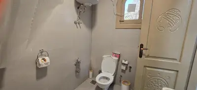 a small bathroom with a toilet and a door at MaMa Africa Nubian Guest House in Aswan
